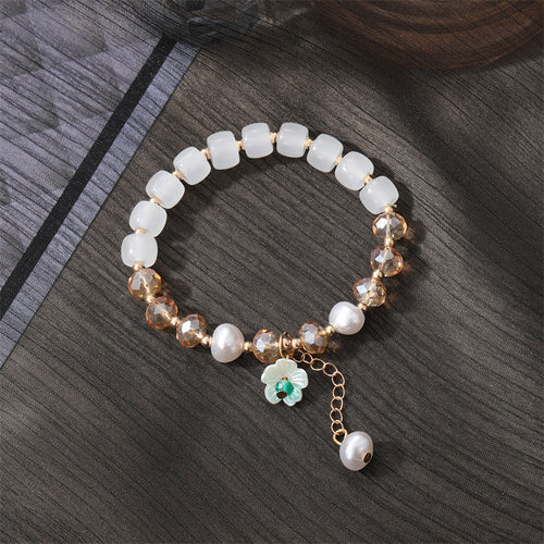 White barrel bead stretch bracelet flower pearl dangle on dark fabric