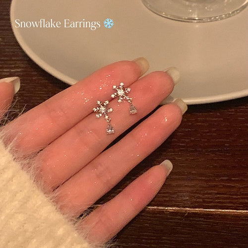 Main image 2 showing small silver-tone snowflakes with clear crystal centers and delicate teardrop dangles, arranged det