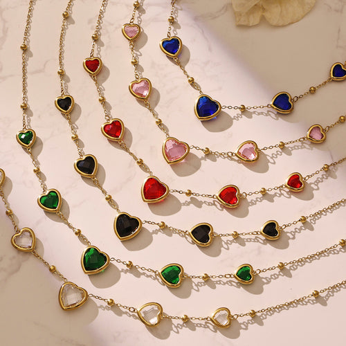 Rows of multicolor gold heart station necklaces on marble