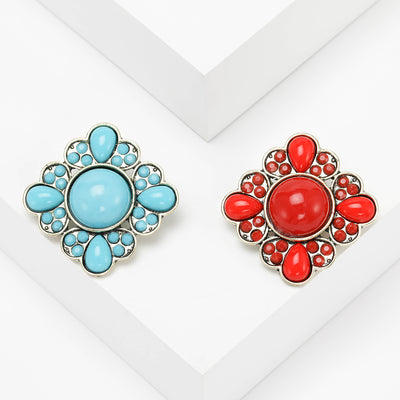 A round floral cluster of smooth colored cabochons and crystals shown on a white background.