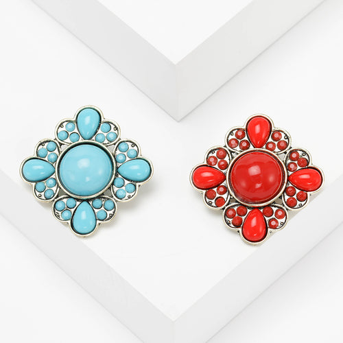 A round floral cluster of smooth colored cabochons and crystals shown on a white background.