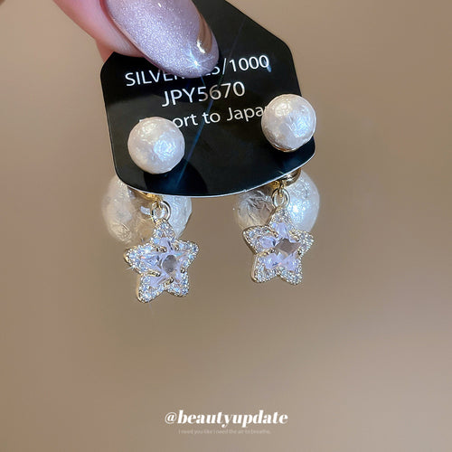 Product close-up of textured white pearl-like studs with clear crystal star and pearl-like drops