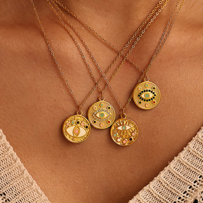 Four gold evil eye enamel coin pendants layered on neckline