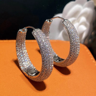 Silver full pave thick hoop pair front angle on orange leather surface