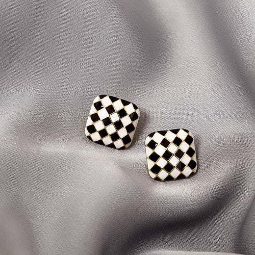 Black white checkerboard square stud earrings pair on gray satin