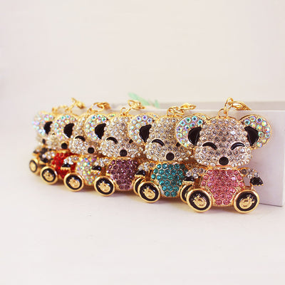Several rhinestone koala keychains are arranged in a row with different colored bodies.