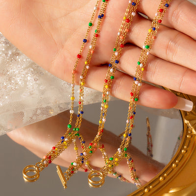 Hand holding three multicolor bead gold multi-strand chains over mirror
