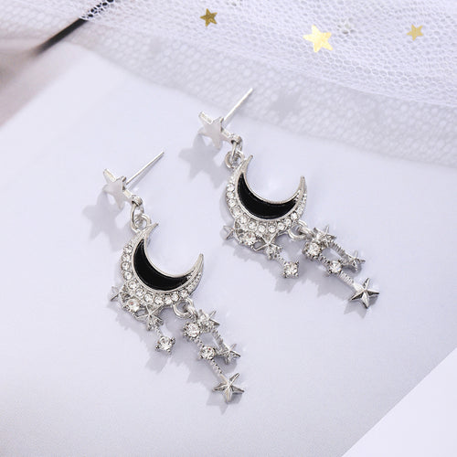 Black enamel crescent moon rhinestone star tassel drop earrings on white fabric