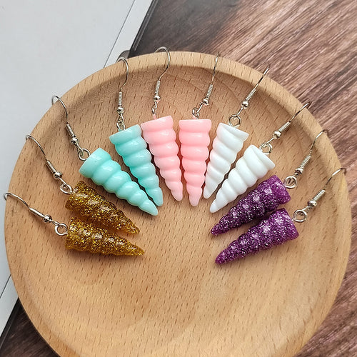 Assorted spiral unicorn horn resin drop earrings in six colors on wooden plate