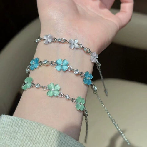 Wrist stack of pink blue and green silver flower charm bracelets