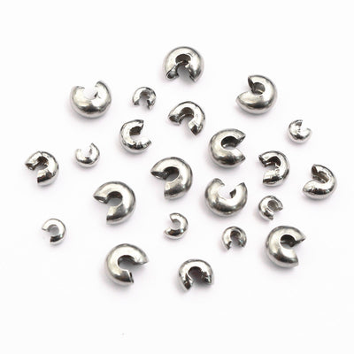 Overview of silver tone half moon open crimp bead cover components arranged on white
