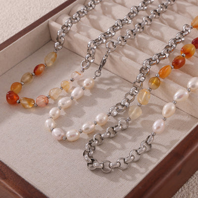Steel chain necklace with pearl and amber stone halves laid in jewelry tray