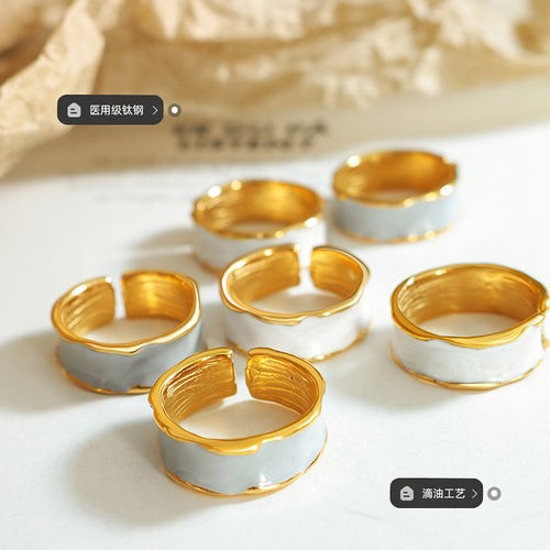 Several gold-rim enamel open rings white and gray on paper surface