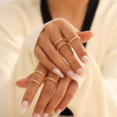 Model hands stacked with multiple gold thin zircon band rings
