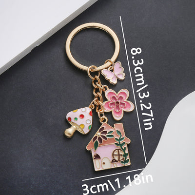 Front product photo of pink mushroom house butterfly and flower enamel charm keychain showing the pictured design arrang