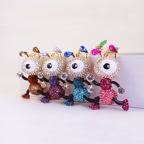 Four one-eyed cartoon ant figures in brown, purple, blue, and pink stand side by side.