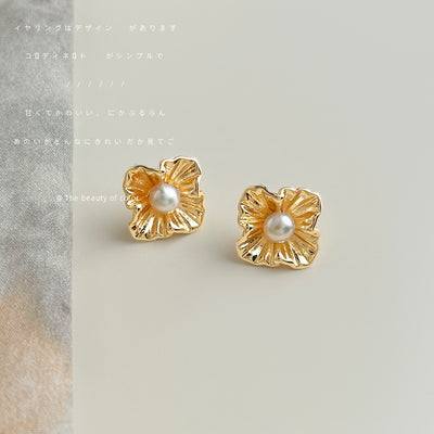 Gold textured flower pearl studs on beige tabletop