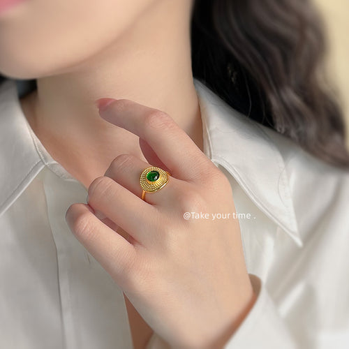 Gold green cabochon ring worn on finger with white shirt
