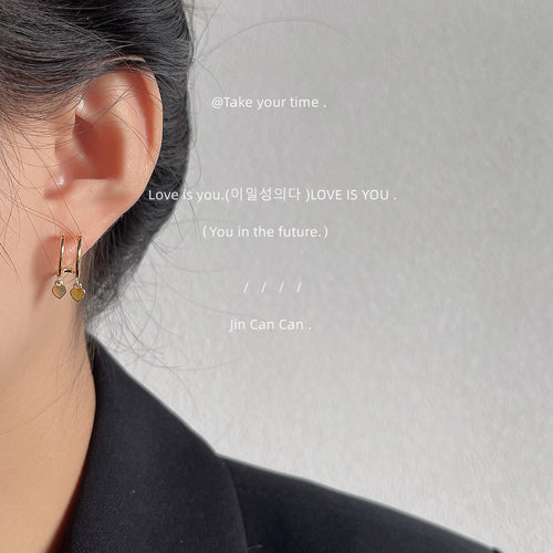 Gold dual heart charm hoop earring worn on ear