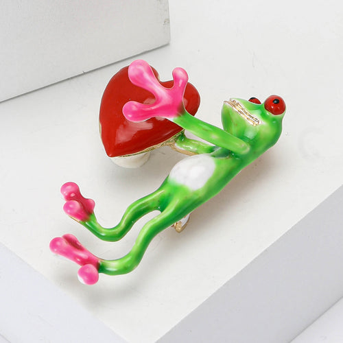frog holding a heart brooch displayed on a product backdrop