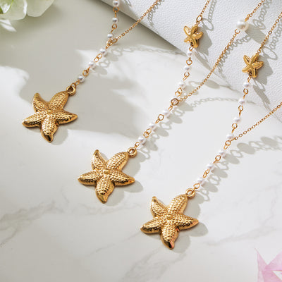 Grouped style view of gold tone starfish and pearl lariat necklace in main image 1.
