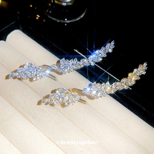 Silver and gold leaf crystal open rings displayed on beige ring rolls