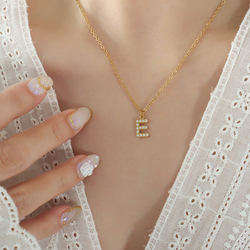 Model wearing gold E letter pendant necklace white lace top