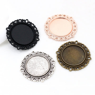 Assorted ornate round pendant bezel trays in four metal finishes arranged together on a plain background