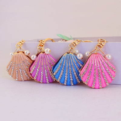 Four scallop shell keychains in peach, purple, blue, and pink arranged together.