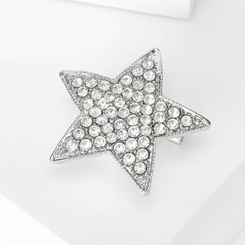 Silver rhinestone star brooch angled on white geometric display