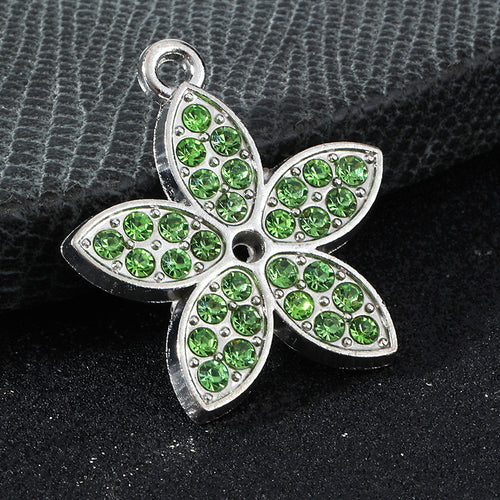 Close-up silver flower charm pave-set with green rhinestones and a center hole