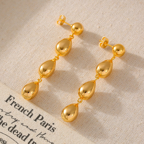 Pair of gold triple teardrop dangles on linen with printed text