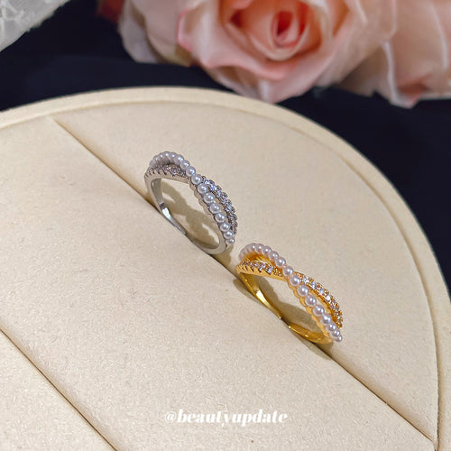 Silver and gold pearl crystal crossed rings on cream jewelry pad