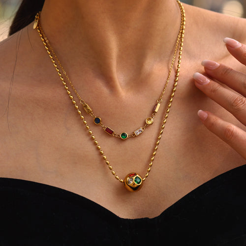 Model wearing layered multicolor zircon and gold ball chain necklaces