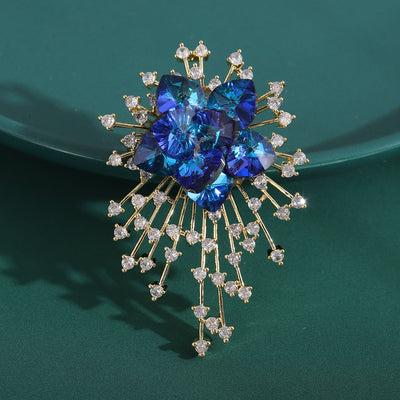 Blue crystal starburst flower brooch on dark green plate