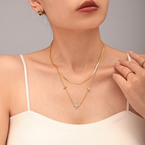 Gold four-leaf zircon necklace layered with snake chain