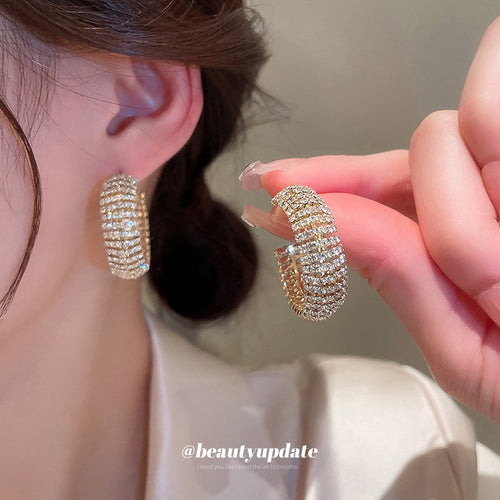 Styled close-up of wide crystal pave hoop earrings