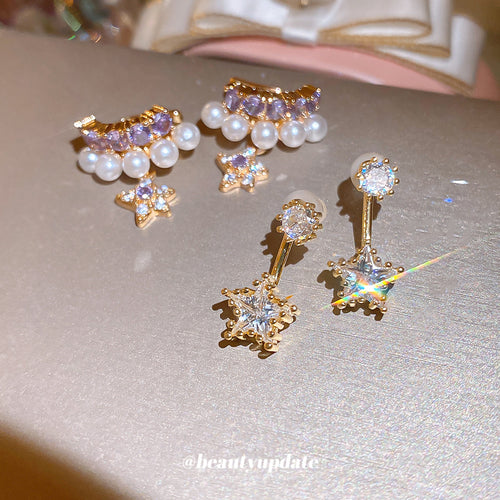 Gold star drop studs and purple crystal pearl ear clips on champagne surface