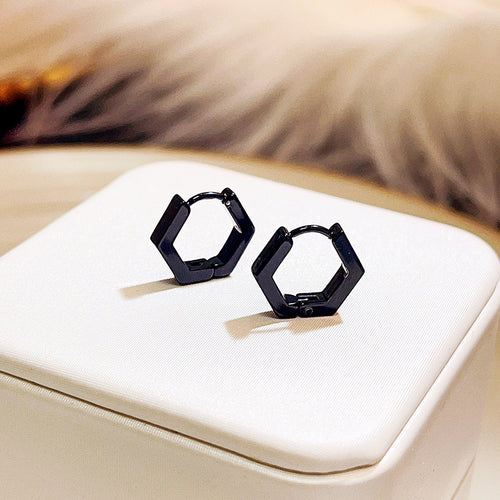 Black matte hexagon huggie hoops on white fabric cushion