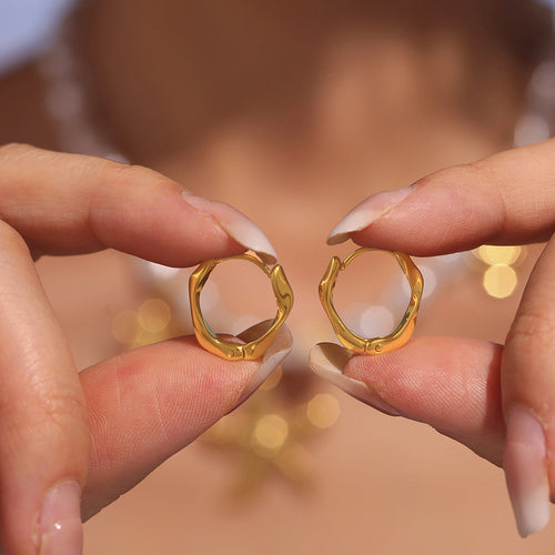 Hands holding open gold twisted geometric mini hoops