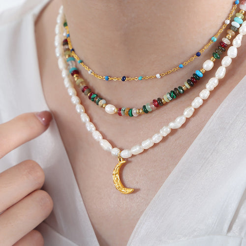 Pearl moon necklace layered with other bead chains on neck