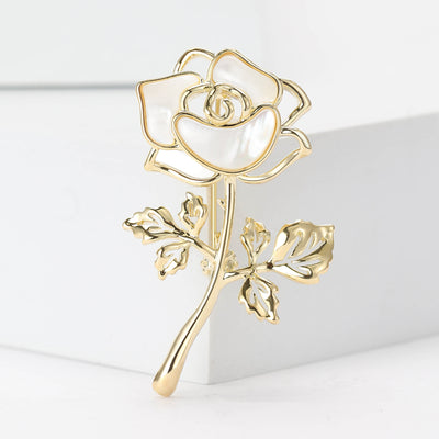 Front view of shell-effect rose stem brooch with open gold tone leaves against a white background.