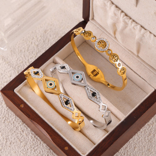 Gold and steel evil-eye and Tree of Life bangles in open jewelry box