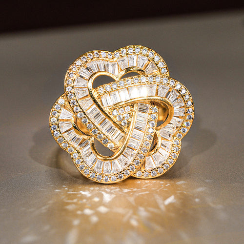 Gold interlaced heart flower ring face sparkling on dark surface