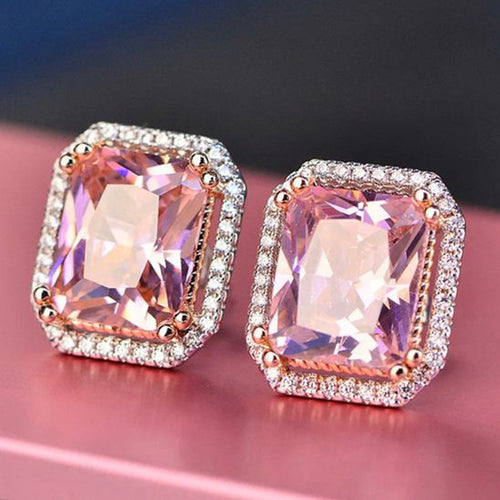 Pink rectangular halo stud earrings on pink surface