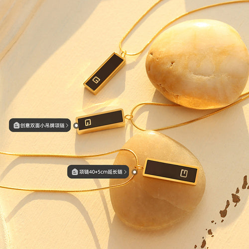 Three black G tag pendants on stones with length labels