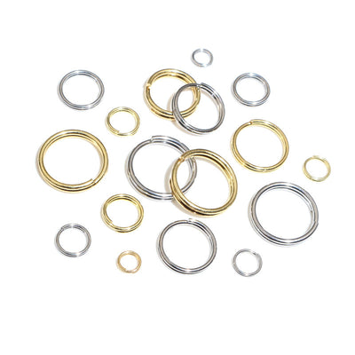 Assorted round split jump rings in gold and silver tones arranged together on a plain background