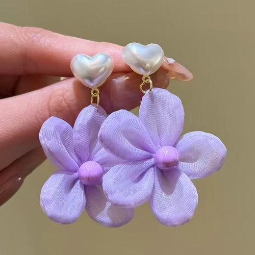 Product close-up of 紫色布艺花朵耳环 showing soft purple fabric flowers suspended from pearly heart-shaped tops