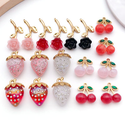Red cherry and strawberry charms arranged on a light background