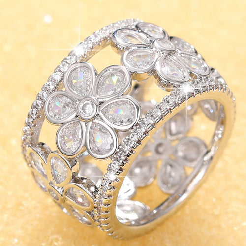 Silver wide flower openwork CZ band ring close-up on gold background
